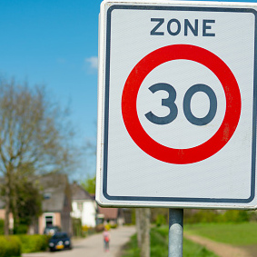 Speedlimit 30 mph zone traffic sign on  acreage, focus on sign, sunny blue sky